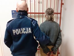 zatrzymana z policjantem stoją na tle kraty