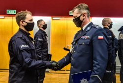 Komendant Wojewódzki Policji we Wrocławiu podaje rękę nowo przyjętemu policjantowi.