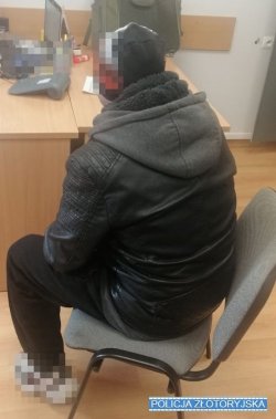 mężczyzna zatrzymany siedzie przy biurku w komendzie