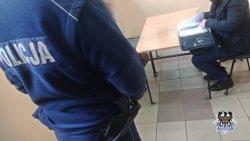 policjant stoi obok męzczyzny siedzącego przy stoliku