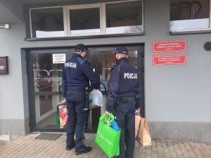 policjanci z torbami z zakupami wchodzą do MOPSu