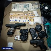 Na zdjęciu widać biurko a na min pieniądze, broń i amunicja zabezpieczone podczas działań policjantów