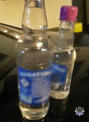 Zdjęcie przedstawia stojące na stole dwie butelki zabezpieczonego denaturatu.