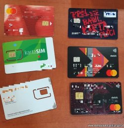 Zdjęcie przedstawia leżące na burku karty bankomatowe i sim