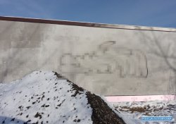 Na zdjęciu widać fragment ściany budynku a na niej napis graficiarza