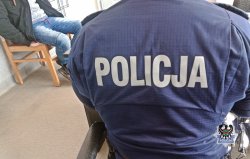 na zdjęciu widać policjanta w mundurze i siedzącego obok na krześle zatrzymanego mężczyznę