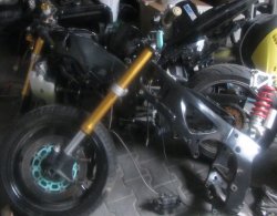 na zdjęciu widać fragment motocykla znalezionego wśród innych przedmiotów w pomieszczeniu gospodarczym