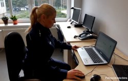 na zdjęciu widać policjantkę w mundurze, która siedzi przy biurku przed komputerem i prowadzi zajęcia online