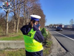 policjantka stoi koło drogi i mierzy prędkość przy pomocy radaru