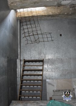 zdjęcie przedstawia pomieszczenie w ziemi będące skrytką na ukradzione rzeczy, widać w środku metalowe elementy i schodki