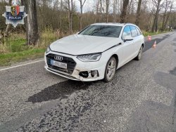 Audi A4 koloru białego zaparkowane na drodze asfaltowej. Pojazd lekko uszkodzony.