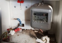 Na zdjęci widać licznik energii elektrycznej oraz kable elektryczne.
