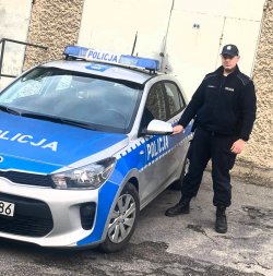 policjant stojący koło radiowozu