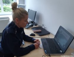 Umundurowana policjantka siedzi w pomieszczeniu przed komputerem.