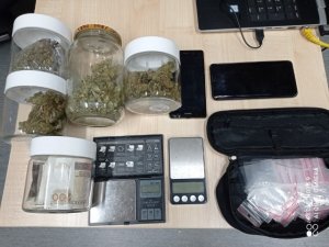 na zdjęciu widać leżące na biurku zabezpieczone pudełka z narkotykami, wagi elektroniczne i telefony