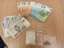 na zdjęciu widać leżące na biurku woreczki z narkotykami i pieniądze w różnej walucie