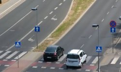 zdjęcie zrobione z góry, widać dwa pojazdy na drodze podczas wyprzedzania na przejściu dla pieszych