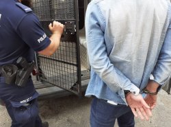 Policjant wkłada do aresztu mężczyznę