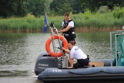 Na zdjęciu widać dwoje policjantów, którzy znajdują się na policyjnej łodzi