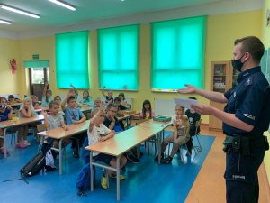 Zdjęcie przedstawia policjanta podczas pogadanki z dziećmi w klasie.
