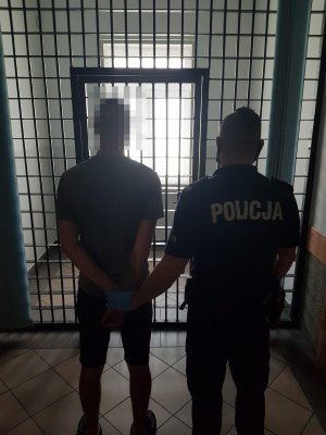 policjant prowadzi zatrzymanego mężczyznę do celi