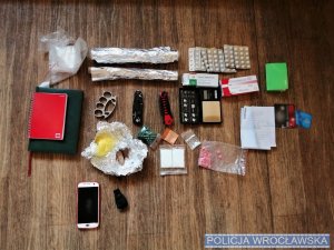 na biurku znajdują się zabezpieczone narkotyki, kastet, notesy tabletki i pudełka z lekami