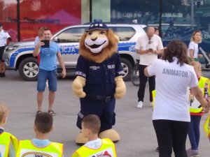 komisarz lew i animatorzy i policjantki tańczą na chodniku pod galerią