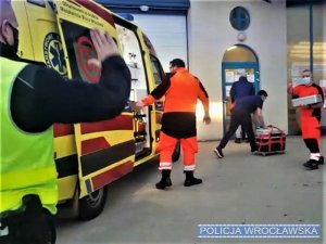 Karetka pogotowia ratunkowego stojąca wraz z ratownikami medycznymi przed wejściem do szpitala
