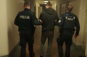 Na zdjęciu policjanci prowadzą zatrzymanego